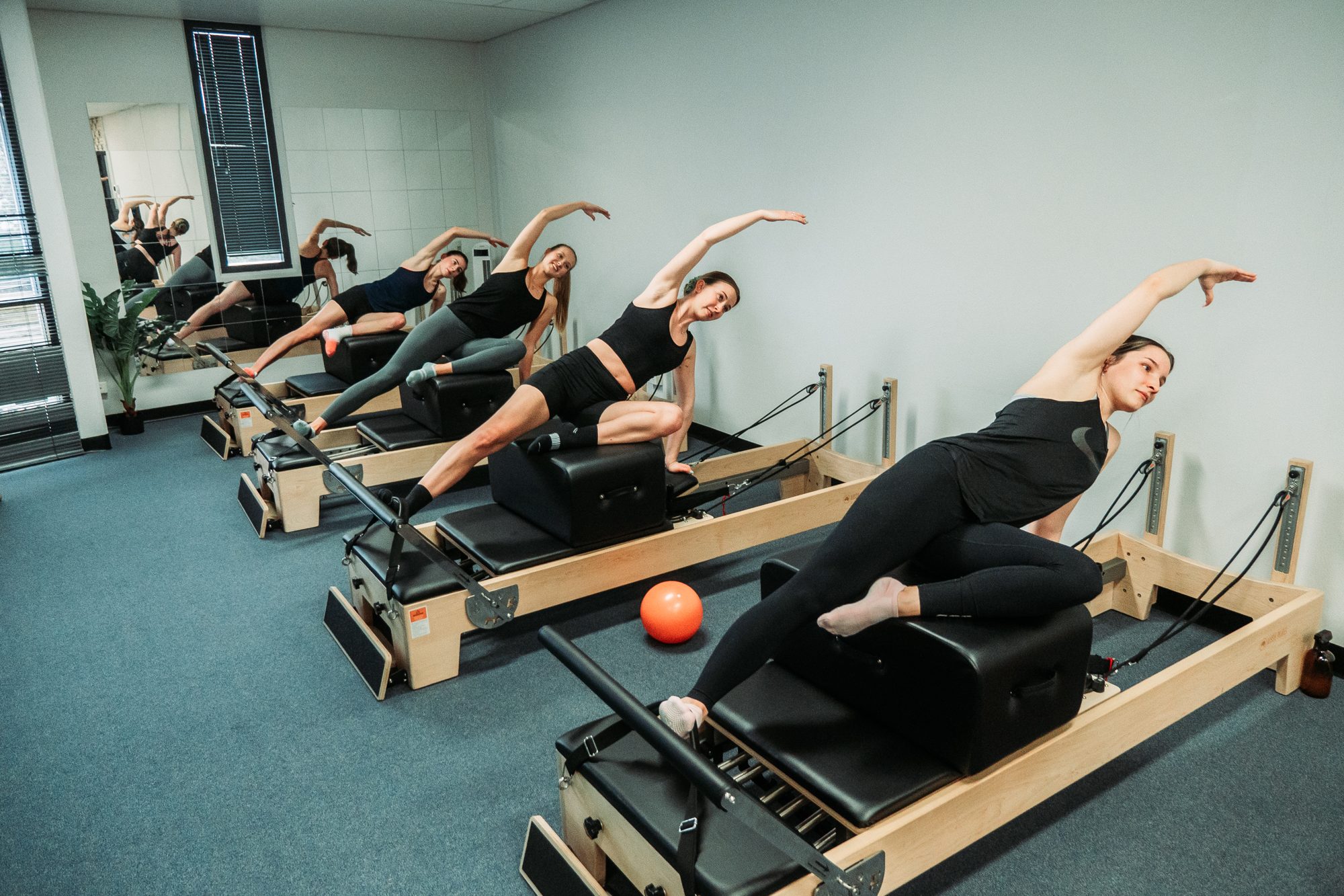 A reformer class stretching together at Pilates Precision