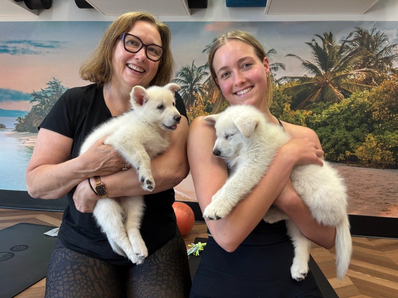 Two Puppy Pilates guests holding puppies
