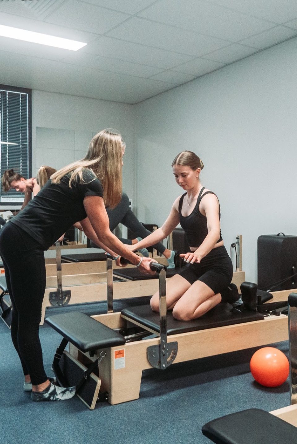 An instructor guiding a client on the reformer